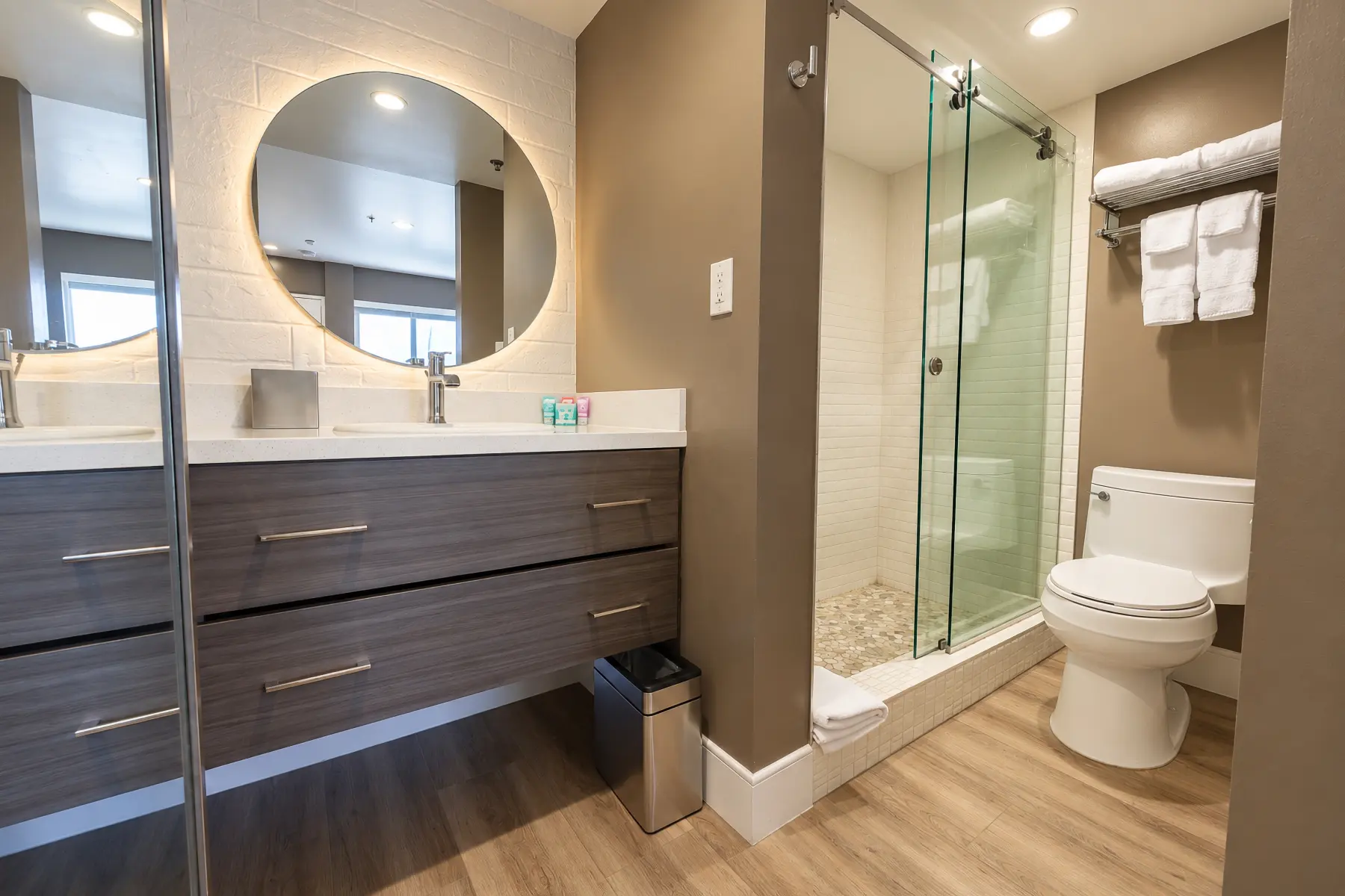 Bathroom with a walk-in shower and a lit round mirror