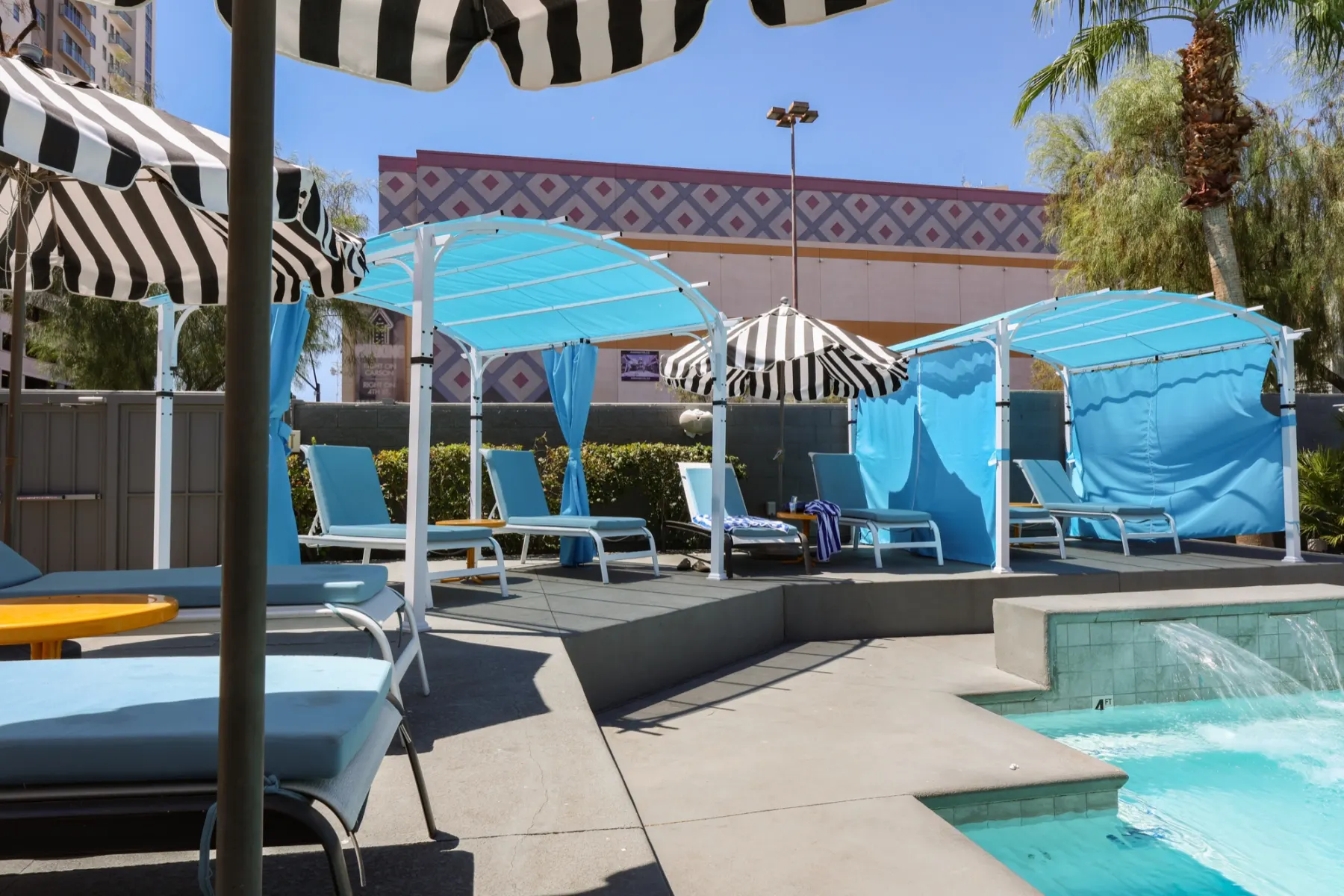Striped umbrellas and blue cabanas beside the pool